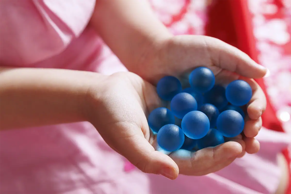 Child holding a handful of small blue decorations against a bright pink dress.