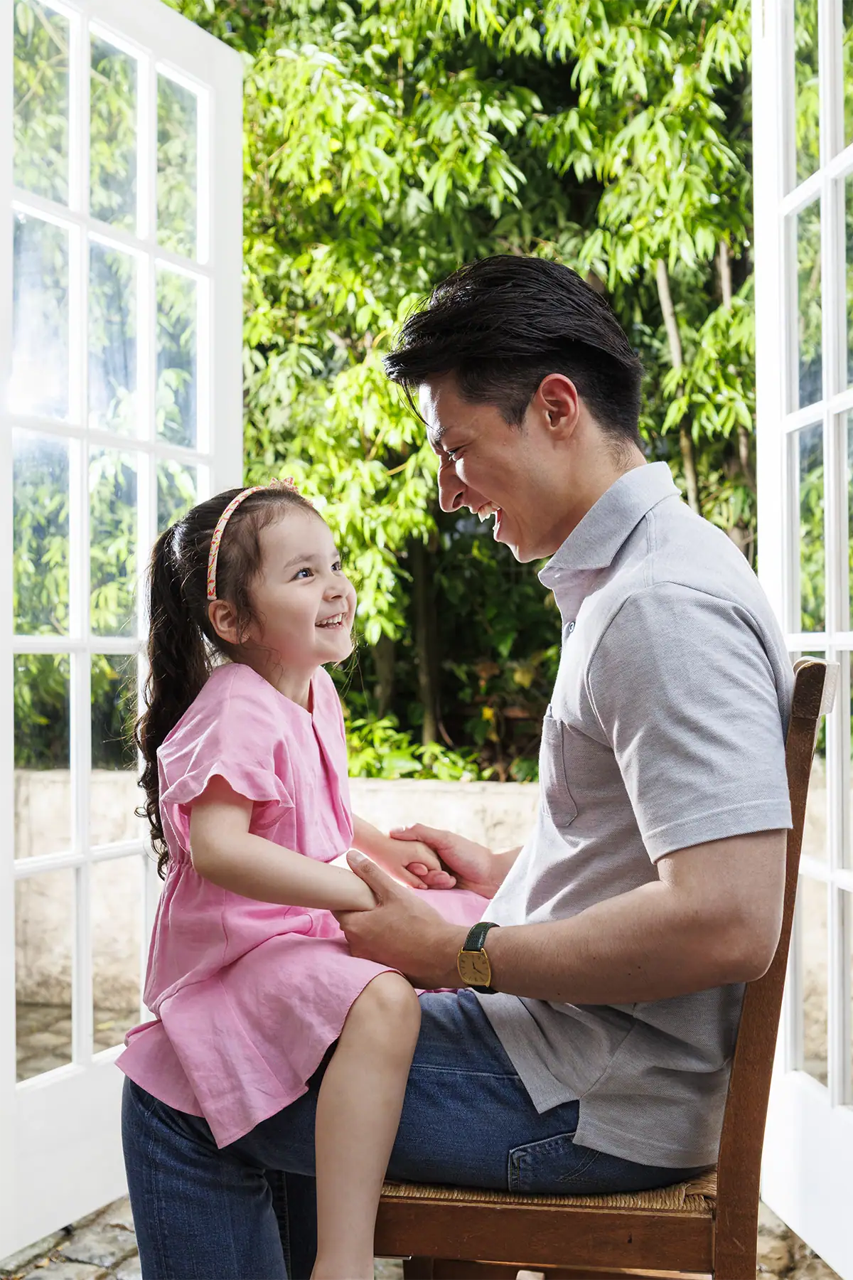Father kneeling beside his daughter near an open doorway during a quiet family moment.