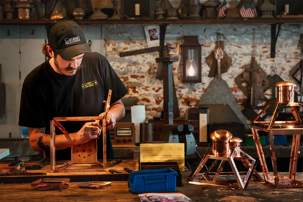 Craftsman working on a copper gas lantern inside a traditional New Orleans workshop, photographed at 45mm F2.8.