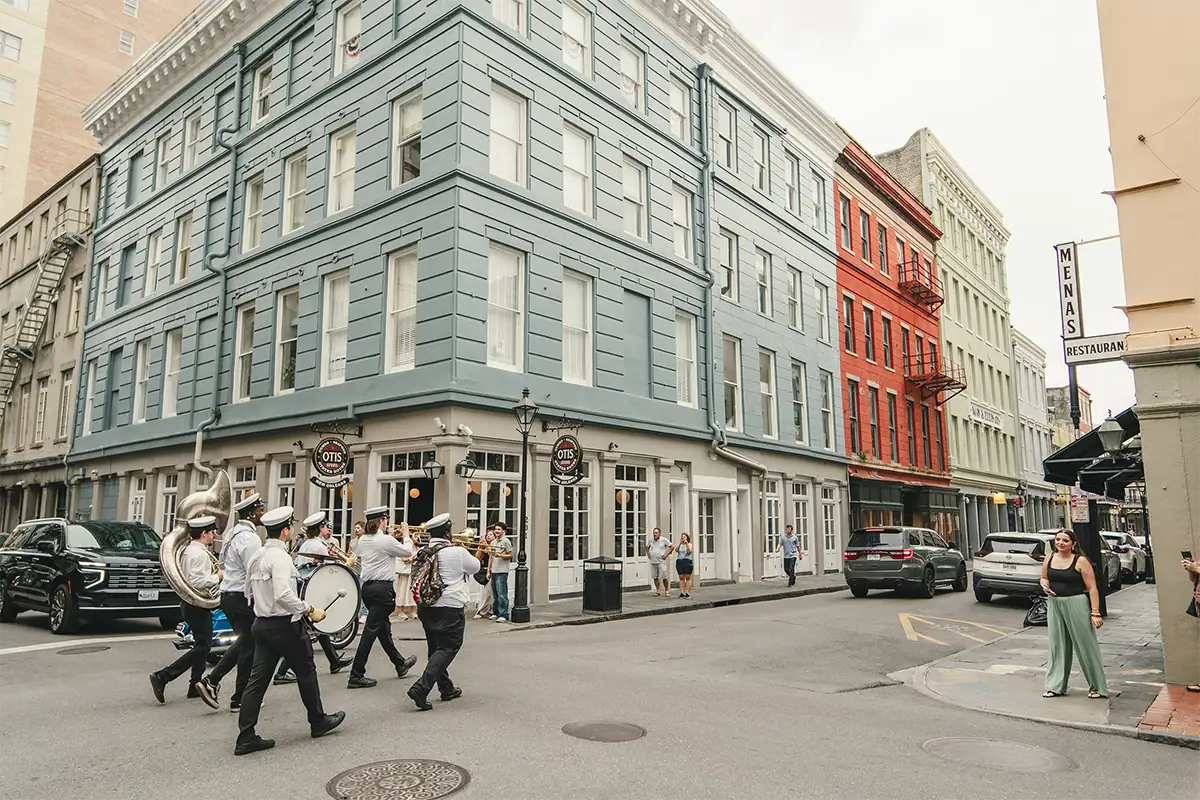 New Orleans marching band walking along a colorful historic street with spectators nearby, photographed at 16mm.
