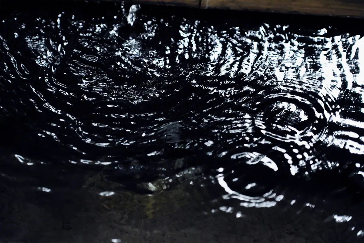 Abstract close-up of shifting ripples and reflected highlights across dark water.
