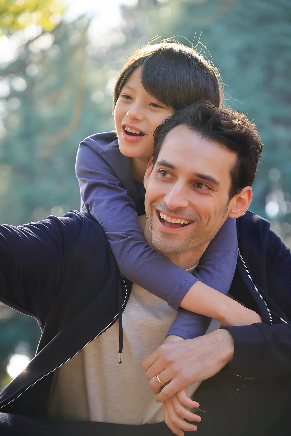 Father carrying his child on his back outdoors in warm backlight, photographed at 70mm with the Tamron 17-70mm F2.8.