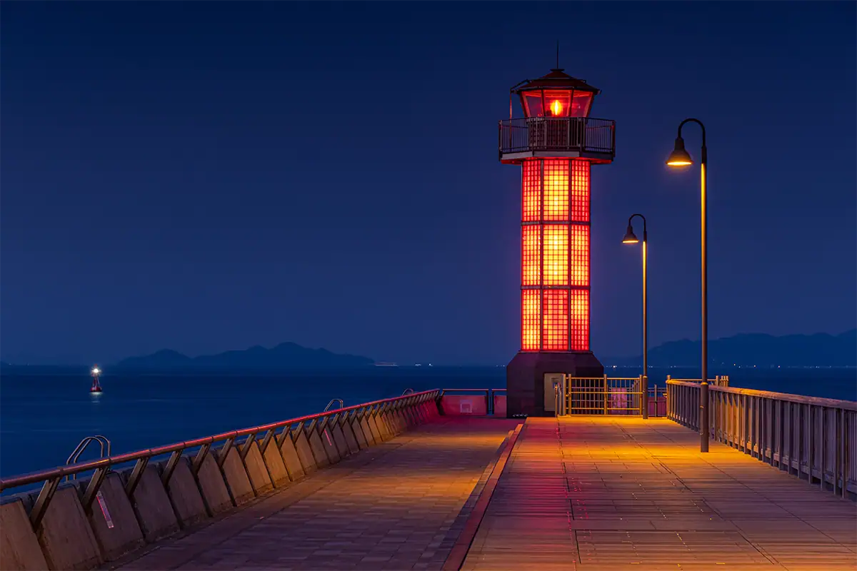 Illuminated red lighthouse against a deep blue evening sky in Shikoku, Japan, photographed with the Tamron 17-70mm F2.8 for Fujifilm X.