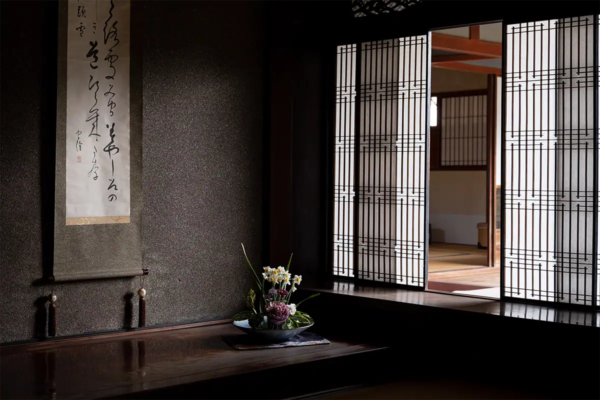 Traditional Japanese interior with a calligraphy scroll, flower arrangement, and shoji screens in Uchiko, Ehime, photographed with the Tamron 17-70mm F2.8 for Fujifilm X.