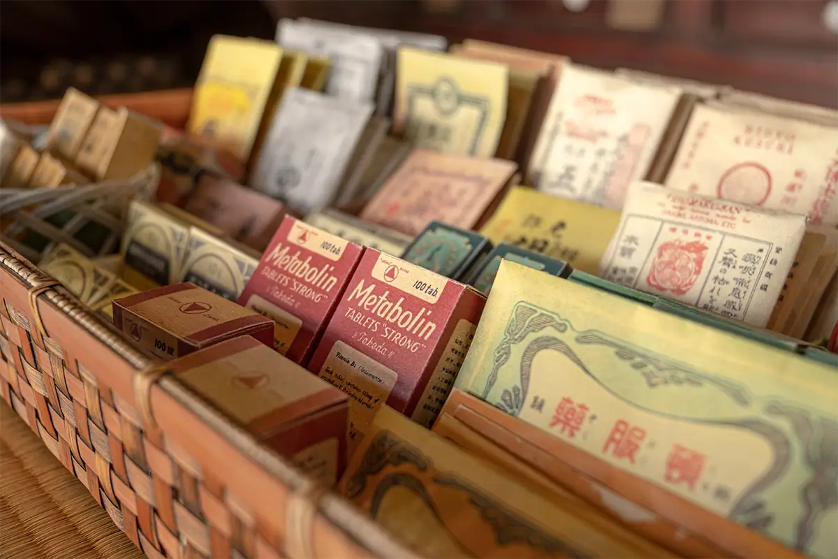 Vintage medicine packages displayed in a woven basket in Uchiko, Ehime, photographed close up with the Tamron 17-70mm F2.8 for Fujifilm X.