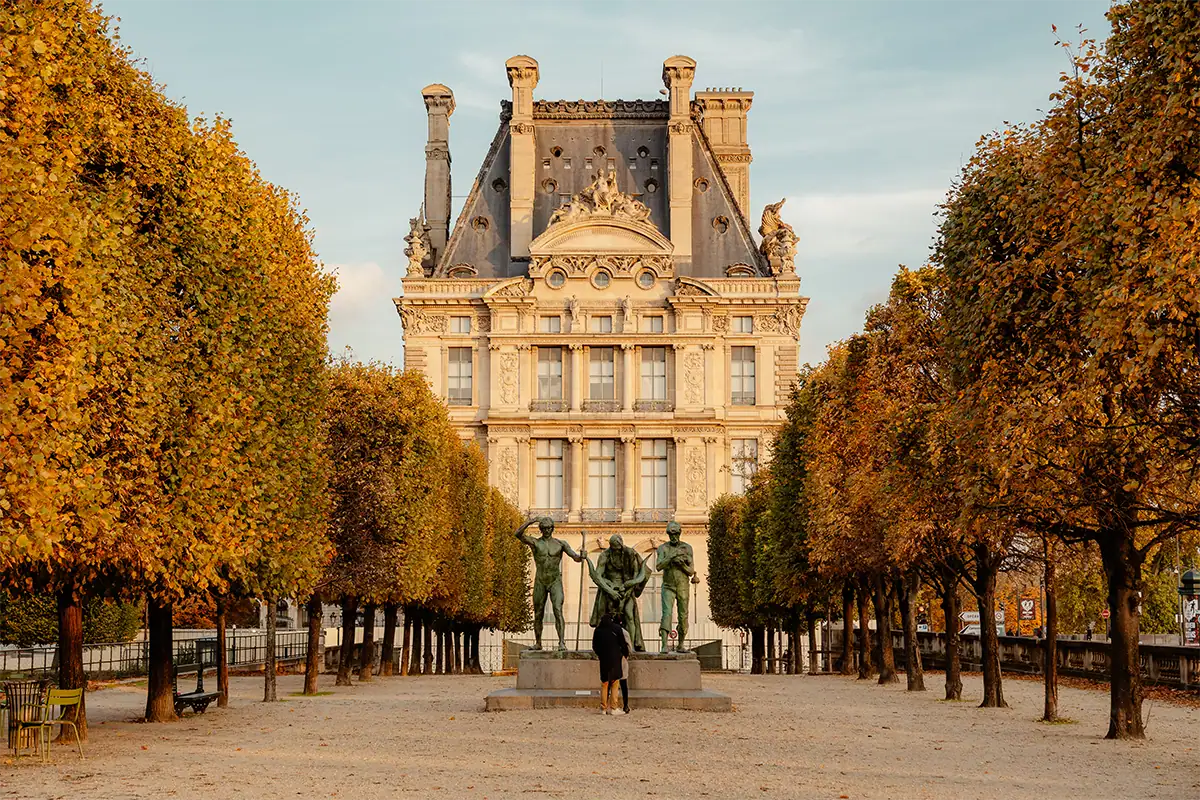 Arquitectura histórica de París enmarcada por árboles otoñales simétricos, fotografiada con el Tamron 17-70 mm F2.8 para Sony E.