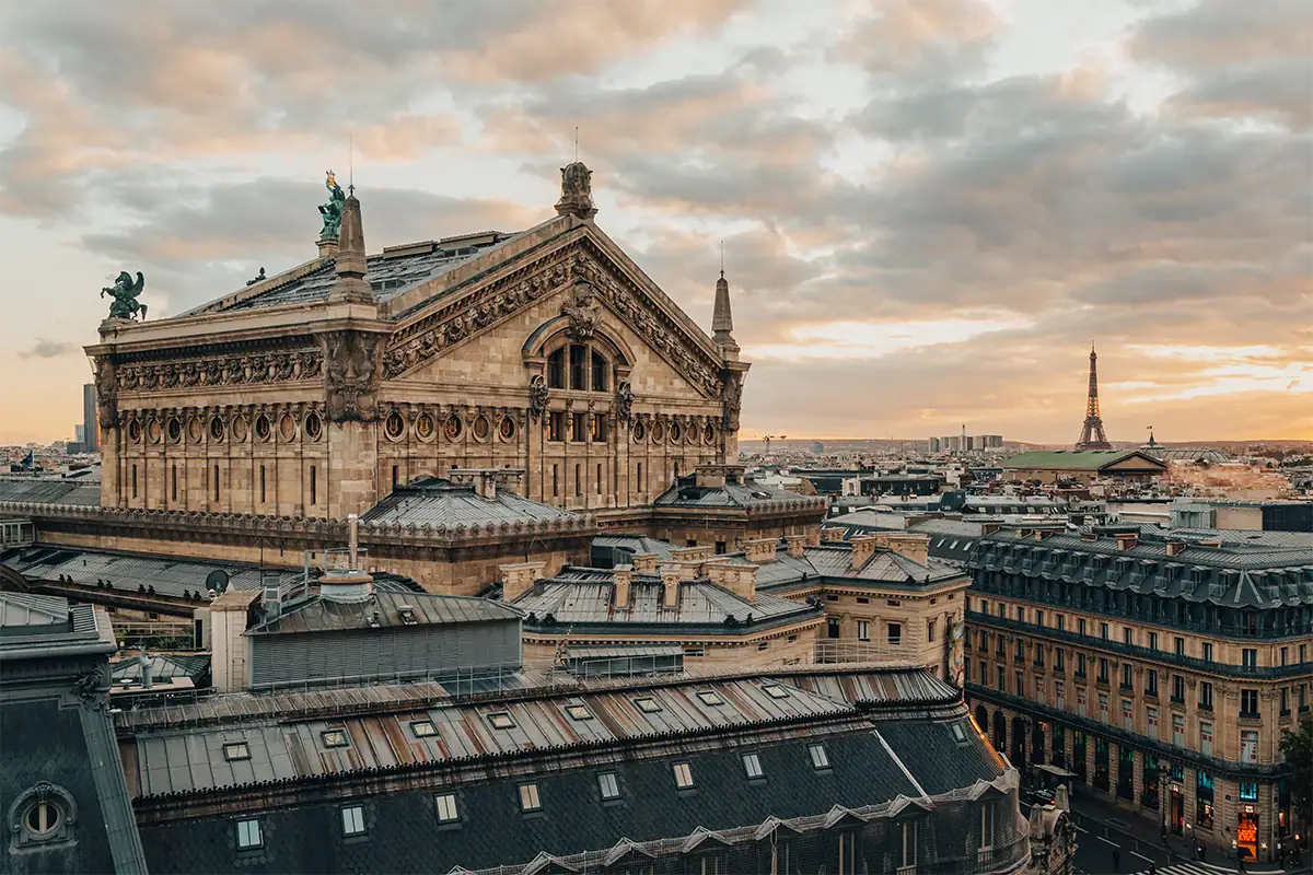 Las azoteas de París y la arquitectura histórica, con la Torre Eiffel a lo lejos bajo las suaves nubes del atardecer, fotografiadas con el Tamron 17-70 mm F2.8.