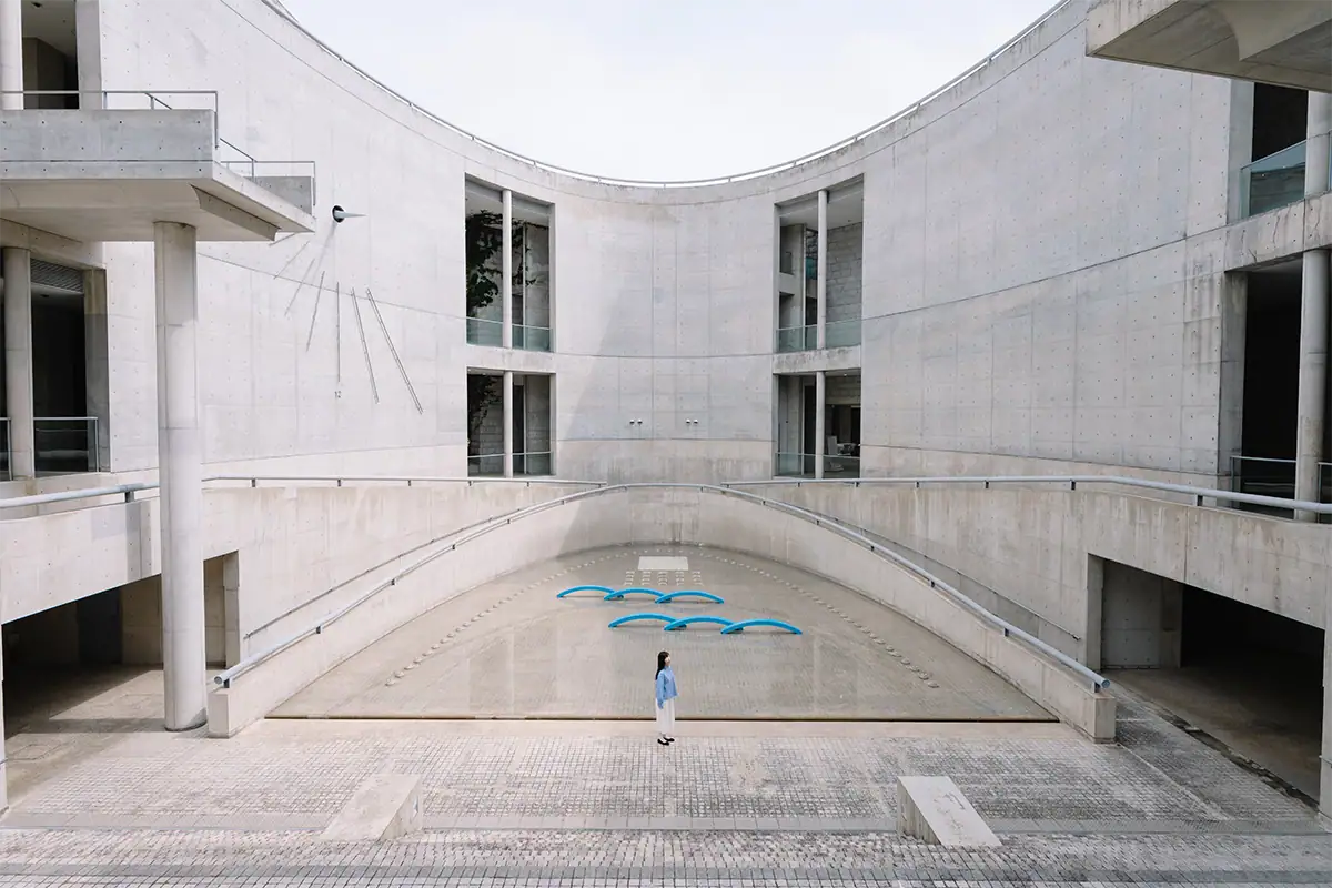 Person standing at the center of curved concrete architecture, showing the expansive 20mm ultra wide-angle perspective.