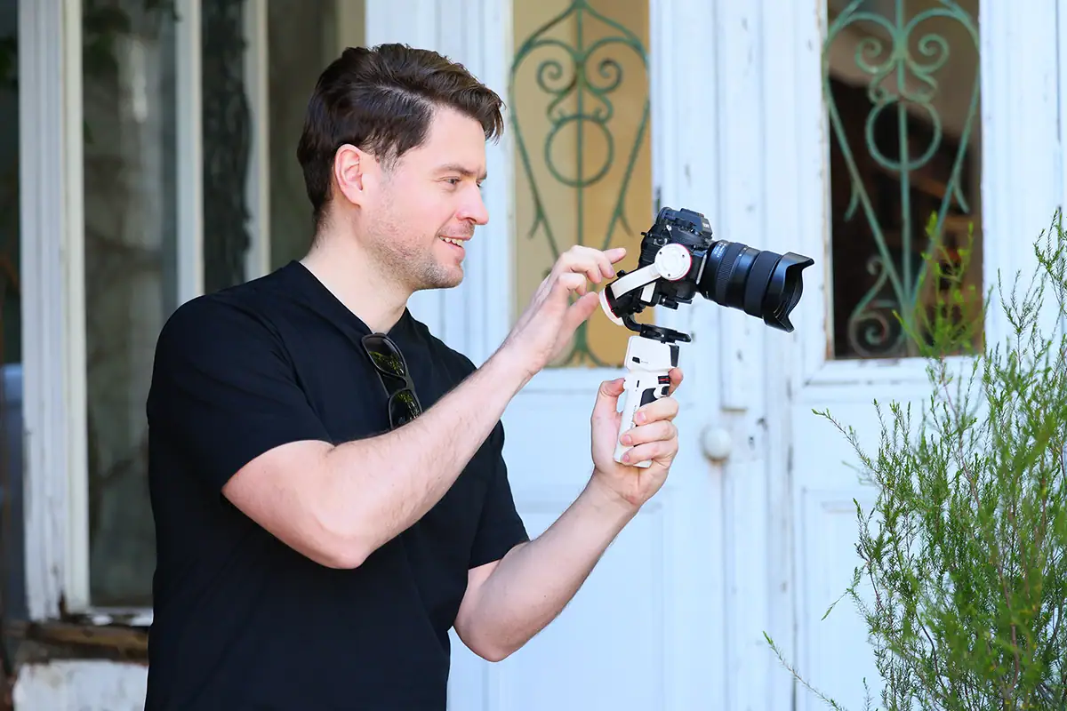 Appareil photo sans miroir équipé d'un objectif Tamron monté sur un stabilisateur portatif permettant de contrôler les mouvements lors de l'enregistrement vidéo.