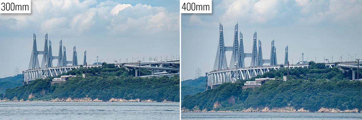 Comparação lado a lado de uma ponte distante fotografada em 300 mm e 400 mm, mostrando um enquadramento mais fechado e maior ampliação do objeto em 400 mm.